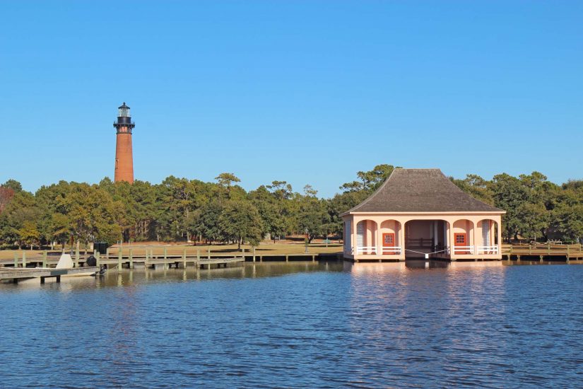 The red brick structure of the Currituck Beach Lighthouse and the pink boathouse at Currituck Heritage Park near Corolla, North Carolina