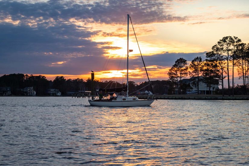 A sailboat returns to a marina at sunset in Oriental, North Carolina.