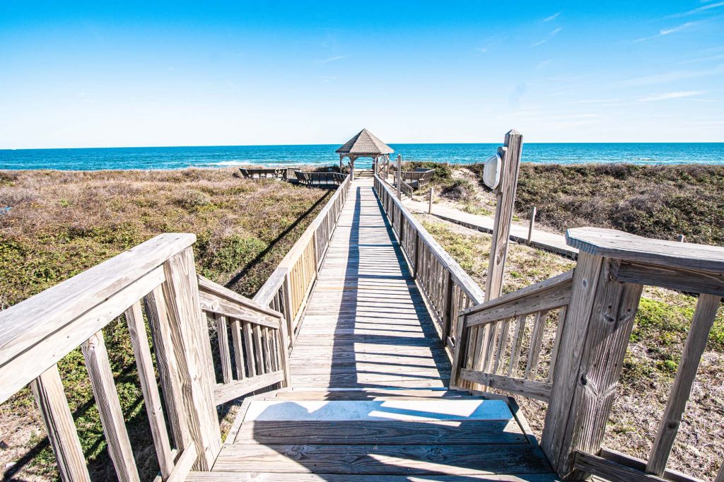 Photo of pathway from resort to the beach with gazebo at the end, showcasing the ocean in the back.
